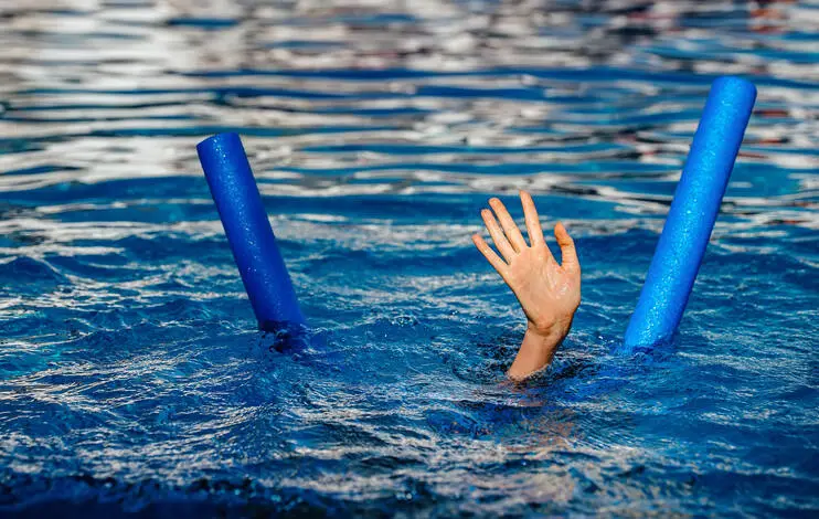 child drowing in the swimming pool , raising hands